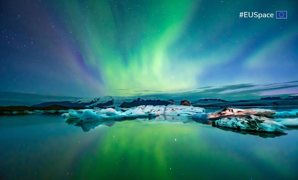 The aurora borealis displays vibrant colors in the night sky, caused by solar rays interacting with the Earth's atmosphere.